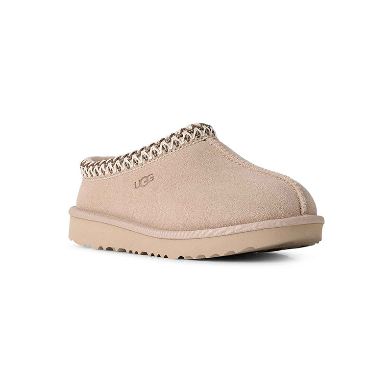 A single UGG slip-on clog shoe in beige suede with a braided trim around the opening and a matching beige sole, shown against a plain white background.