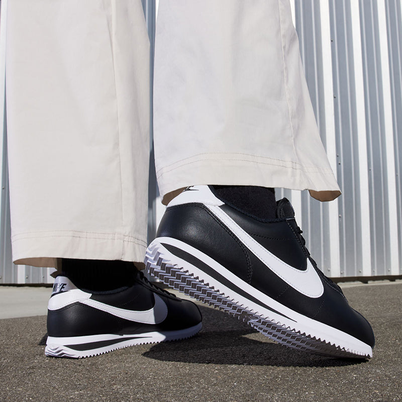 Woman wearing Nike Cortez sneaker in black/white.