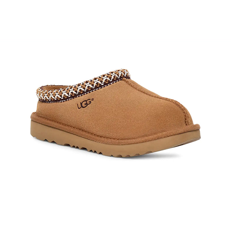 A kid's chestnut-colored suede UGG slipper with a braided trim and a visible UGG logo on the sole.