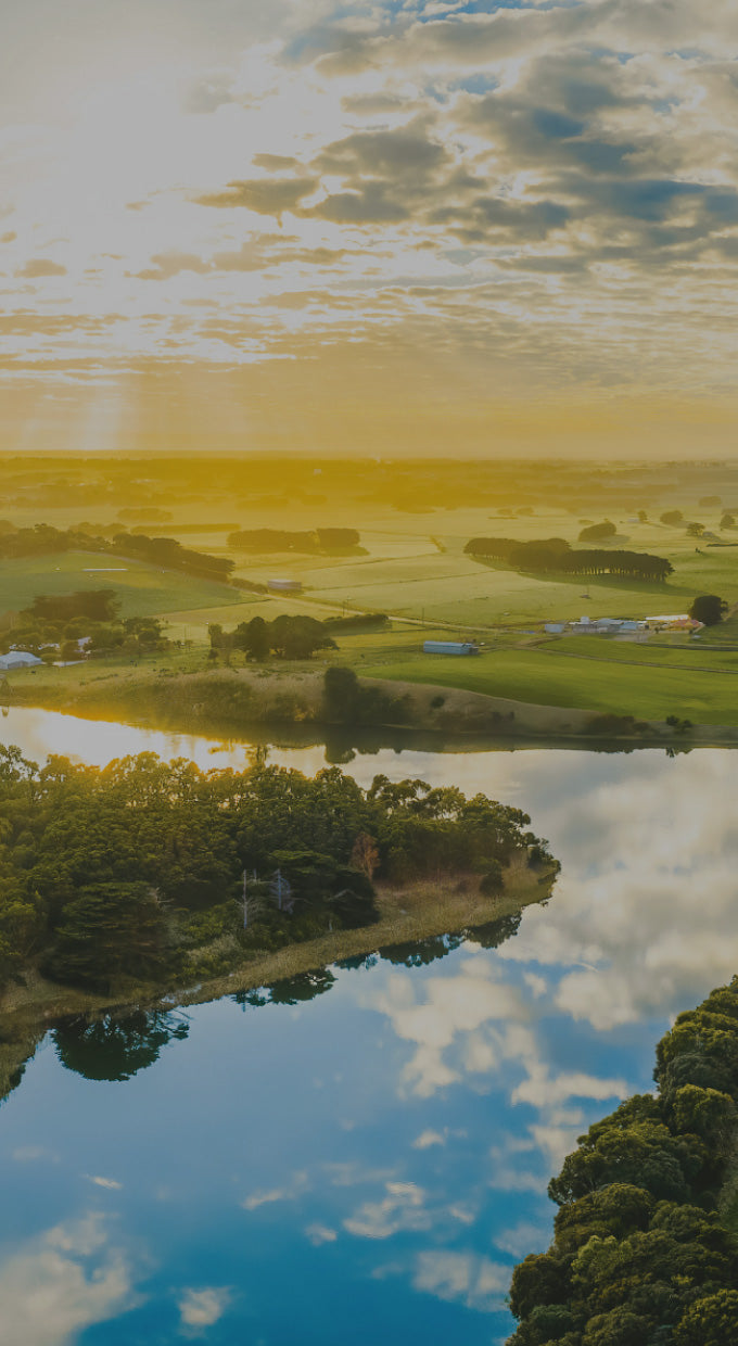 Sun shining down on a green field and river.